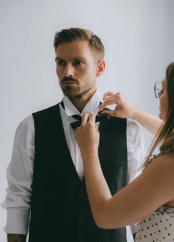 wedding planner qui habille un marié pendant son stage